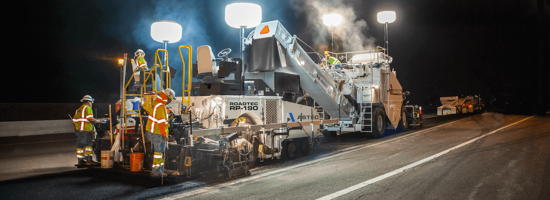 Roadtec RP-190 highway class asphalt paver paving at night with a Roadtec Shuttle Buggy Material Transfer Vehicle