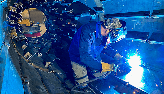 Welder inside of an asphalt drum welding flights