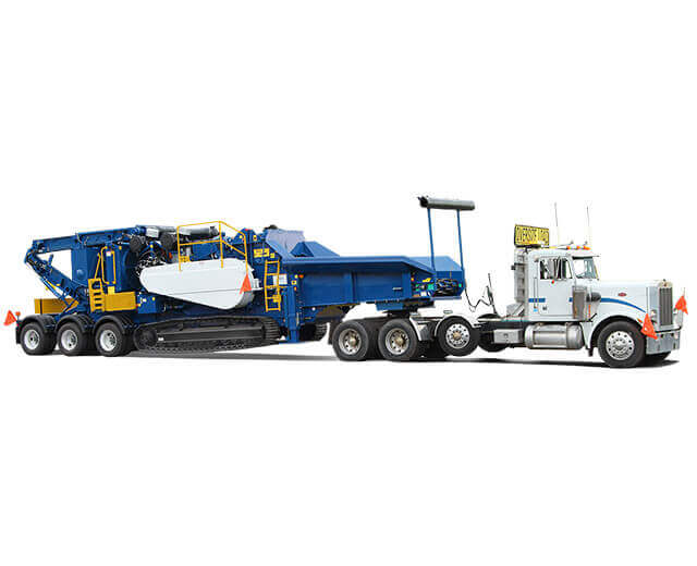 An Astec Peterson tracked horizontal grinder being transported with a semi and a tow dolly.
